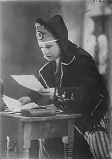 Beniamino Gigli in the opera, looking intentently at documents on a table