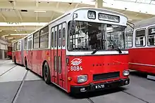 A red and white articulated bus, numbered 8084