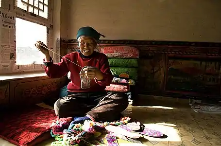 Making shoes on a kang during the day, Yimatu, Chongli District, China. Note bedding, most of it folded and stacked.