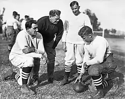 3 men crouched, one standing