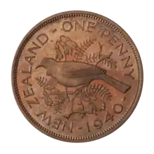 A proof penny featuring a tūī bird perched atop the branch of a kōwhai tree, surrounded by flowers and leaves, and encircled by the text "NEW ZEALAND - ONE PENNY - 1940"