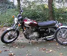 Red-and-white motorcycle, parked on fallen leaves