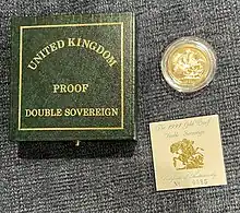 A gold coin together with a small certificate and the green box they have been packaged in