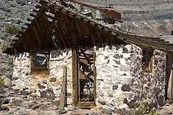 Abandoned bunkhouse at the Bonnie Claire Mine; ruins of the mine shaft head in the background.