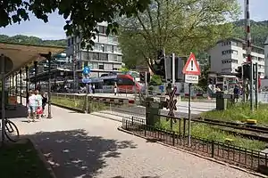 Gray-and-red train at island platform; a grade crossing links the ferry terminal to Seestraße