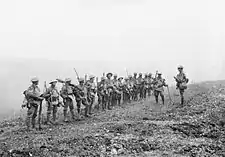 An Australian Lieutenant addressing his platoon before the advance onto Harbonnières which is obscured by smoke from heavy shellfire.