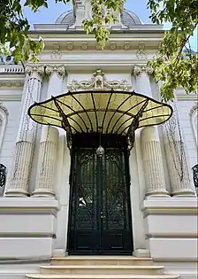 Wrought iron door with a glass and metal awning at the top, at the entrance of the George Deșliu House on Bulevardul Dacia, Bucharest, by Ernest Doneaud, 1912