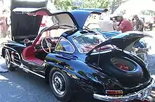 A black coupe with its bonnet, both doors, and boot open