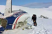 torn aircraft structure standing on snow, with a man standing next to it