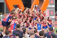 A group of women celebrating and holding a trophy aloft