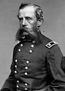 Head and shoulders of a white man with bags under his eyes and a large, bushy mustache and connected sideburns. He is wearing a double-breasted military jacket with two stars on a patch on the shoulder.