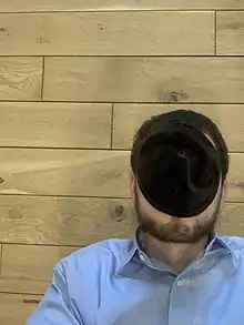 man lying on a floor using a kippah to block light