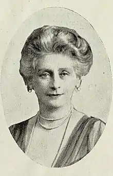 older white woman with bouffant gray hair, wearing pearls or beads.