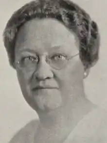 A middle-aged white woman with short coiffed hair and light eyes, wearing glasses