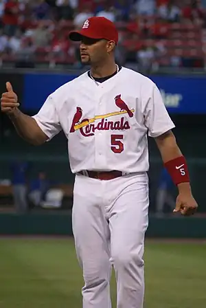 A man wearing a uniform that shows two cardinals sitting on a baseball bat