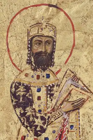 Miniature of a crowned bearded man in gold and purple robes, holding a book, on golden background