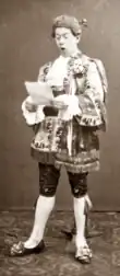 Clean-shaven white man in 18th century costume, reading a letter and looking shocked