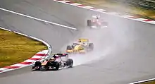 Formula One cars being driven in wet-weather conditions