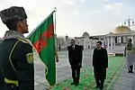 A Turkmen color guard lowering the national flag in the present arms position.