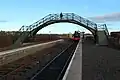 The northern (Alnmouth) end of the station platforms with the station footbridge in the foreground and Ex-NCB Hunslet Austerity 0-6-0ST No. 60 (works No. 3686), taking on water in the background.