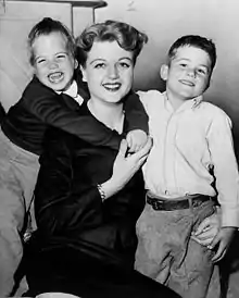 A young white woman with a girl on the left side and a boy on the right, posing together for a photograph