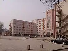  A large square with a fountain in the middle sits before several buildings with a pink rendering. The buildings are used for teaching as part of Anshan Normal University.