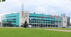 Arena exterior clad in white and turquoise siding with three floors of glass windows, including a green area with flags of countries participating in the 2006 International Ice Hockey Federation World Championship.