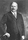 A black-and-white photograph of a man in a suit with a tie.