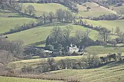 Large house nestling  amongst trees and fields