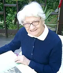 Portrait photo of Dr. Asuman Baytop reading in a chair outside