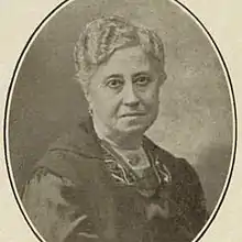 Sepia oval portrait photograph of an old woman with white hair, wearing a dark dress.