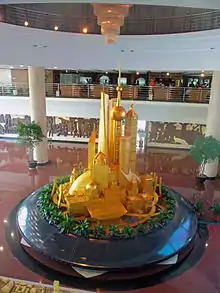 A round platform with golden scale models of buildings in Shanghai, seen from the upper floor of an artium