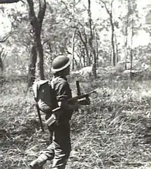 A soldier advances through the bush with a submachine-gun during training