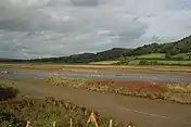 Three wooded hills loom high above a muddy estuary