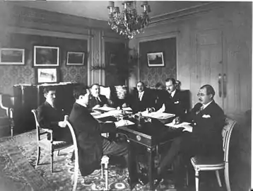 Azerbaijani delegation in Paris at the Claridge Hotel during the Paris Peace Conference, 1919. The tricolour flag of the ADR is visible in the background, on the chest of drawers.