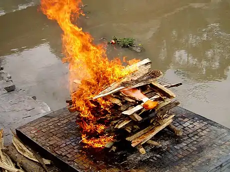 Image 15A Hindu cremation rite in Nepal. The samskara above shows the body wrapped in saffron on a pyre. (from Samskara (rite of passage))