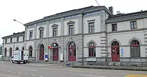 Wide, two-story building with arched doorways and windows