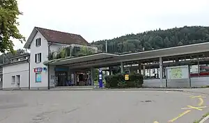 Two-story building with gabled roof and adjoining canopy-covered platform