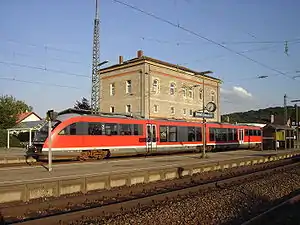 Red train in front of three-story building