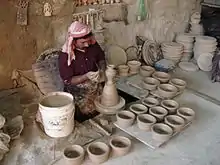 Image 23An artisan making pottery using the traditional mud and water mixture on a revolving wheel. (from Bahrain)