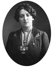 Portrait of a woman with a braided bun in a dark suit adorned with a group of medals