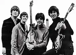 A black and white photograph of the Beatles holding their guitars.