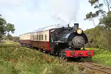 Steam locomotive No. 4 hauls a small tourist train down a straight portion of the railway