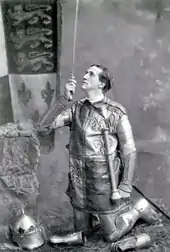 Young white man, clean shaven, in armour and brandishing a sword