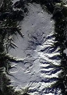 An overhead view of an oval-shaped alpine plateau covered with snow.