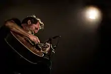 Bill Orcutt playing acoustic guitar onstage