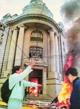 Two rioters stand outside of the burning Vice Presidency Office.