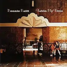 The album cover for Takin' My Time. It features a photograph of Raitt standing underneath an archway at a train station. Two children sit on a bench to the right of the archway.