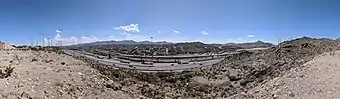 A panoramic view from Sun Bowl Drive at the University of Texas at El Paso, toward the nearby residential neighborhood of Ciudad Juárez, Chihuahua, Mexico, about 350 m away.  This pass full of transportation arteries is the "Paso del Norte" after which El Paso is named, the route of the Camino Real de Tierra Adentro (royal road of the interior land) from Mexico to Santa Fe.  In this narrow valley are the Interstate 10 freeway, the under-construction (in August 2018) Border West Expressway, the Union Pacific and BNSF railroads, US Highway 85 (Paisano Drive, CanAm Highway), a border fence, the American Canal, and the Rio Grande.   The new expressway will mostly occupy space above the railroad tracks.