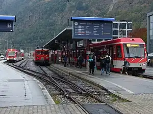 Trains on tracks and canopy-covered platform with departure board